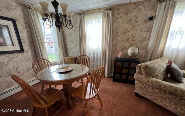 dining space featuring dark colored carpet, a drop ceiling, and an inviting chandelier