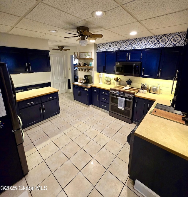 kitchen with blue cabinets, a paneled ceiling, light tile patterned floors, ceiling fan, and stainless steel appliances