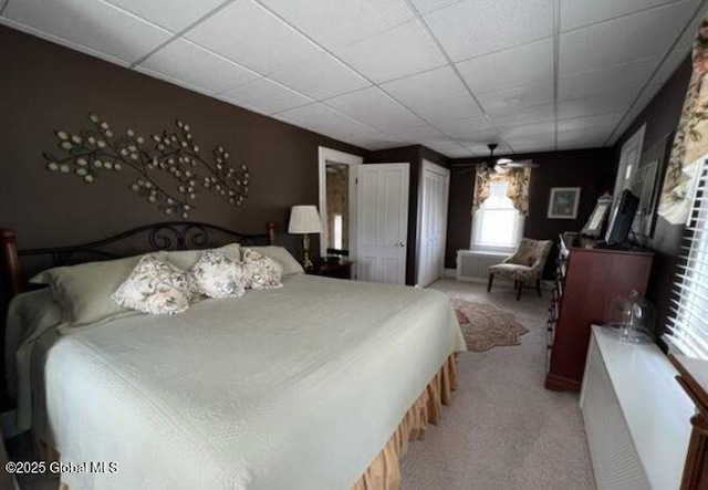 bedroom with a paneled ceiling and light colored carpet