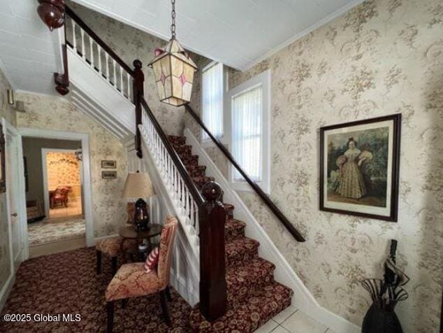 staircase with ornamental molding and tile patterned floors