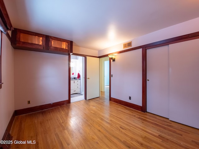 unfurnished bedroom with multiple closets and light hardwood / wood-style flooring