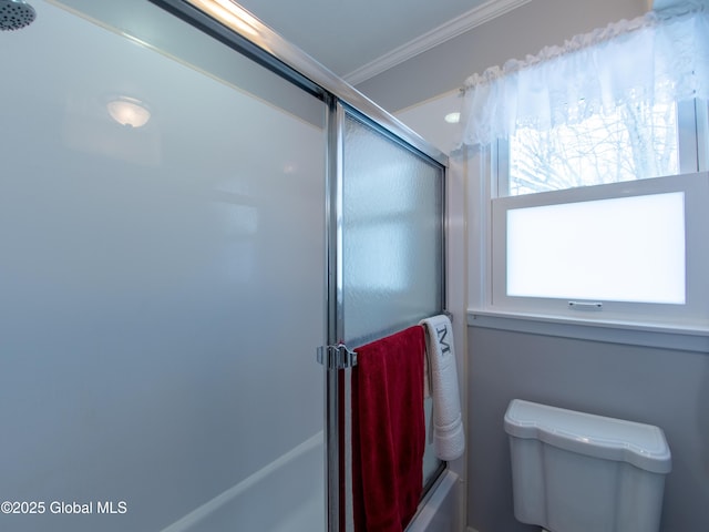 bathroom featuring crown molding, shower / bath combination with glass door, and toilet