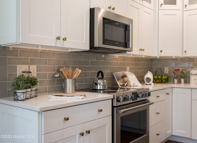 kitchen with backsplash, stainless steel appliances, and white cabinets