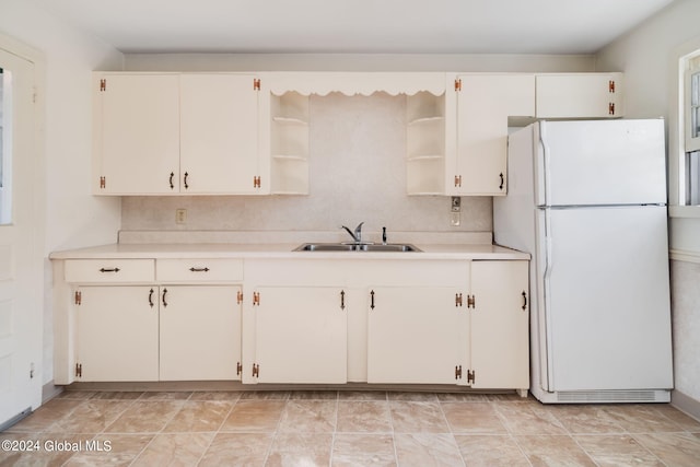 kitchen featuring white refrigerator, white cabinetry, and sink