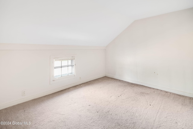 unfurnished room with vaulted ceiling and carpet floors