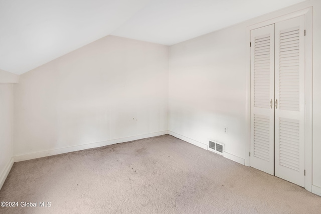 unfurnished bedroom with vaulted ceiling and carpet floors