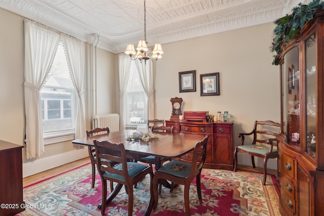 dining area featuring plenty of natural light, a chandelier, light hardwood / wood-style flooring, and radiator heating unit