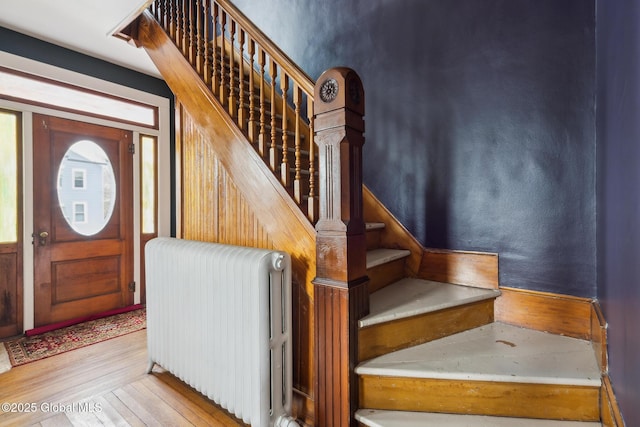 staircase with hardwood / wood-style floors and radiator heating unit