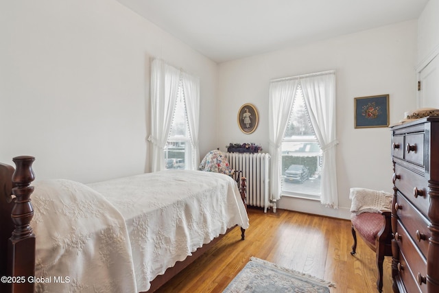 bedroom with radiator heating unit and light hardwood / wood-style floors