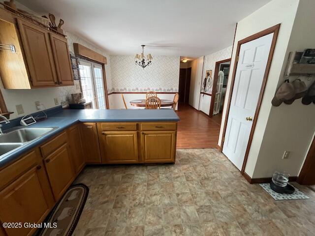 kitchen with hanging light fixtures, kitchen peninsula, sink, and a chandelier