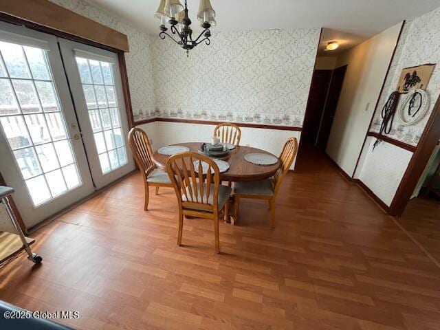 dining space with french doors, plenty of natural light, hardwood / wood-style floors, and a notable chandelier