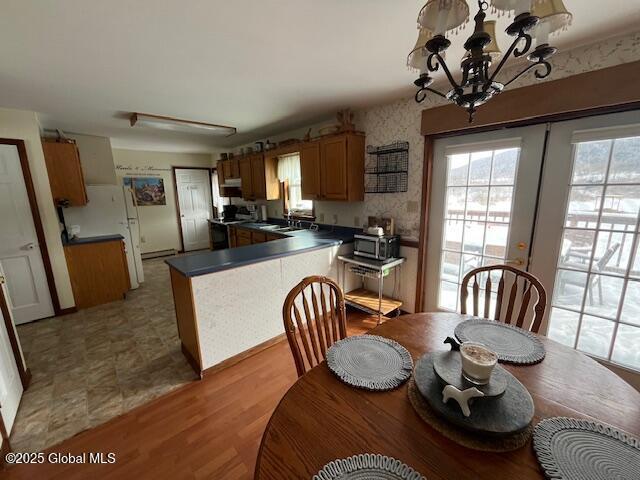 kitchen with pendant lighting, sink, a notable chandelier, light hardwood / wood-style floors, and french doors