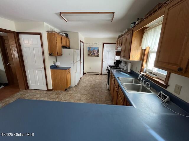 kitchen featuring white refrigerator, gas range, and sink