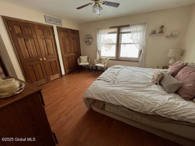 bedroom with multiple closets, ceiling fan, and hardwood / wood-style floors