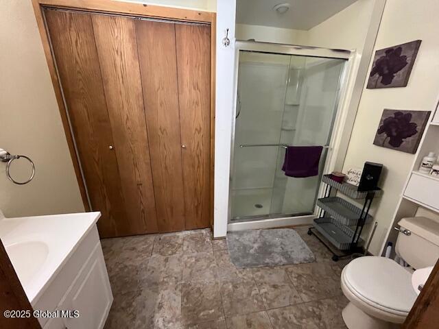 bathroom with vanity, a shower with door, and toilet