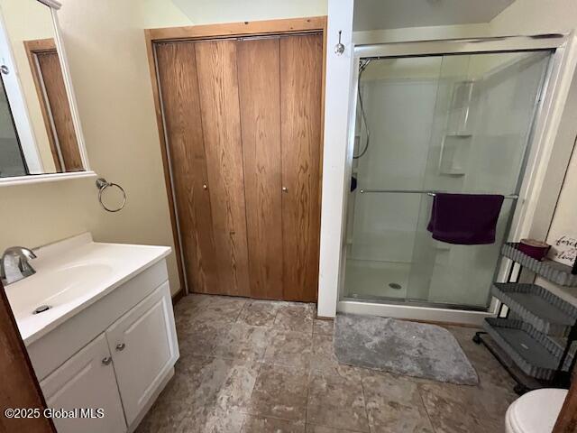 bathroom featuring vanity, toilet, and a shower with shower door