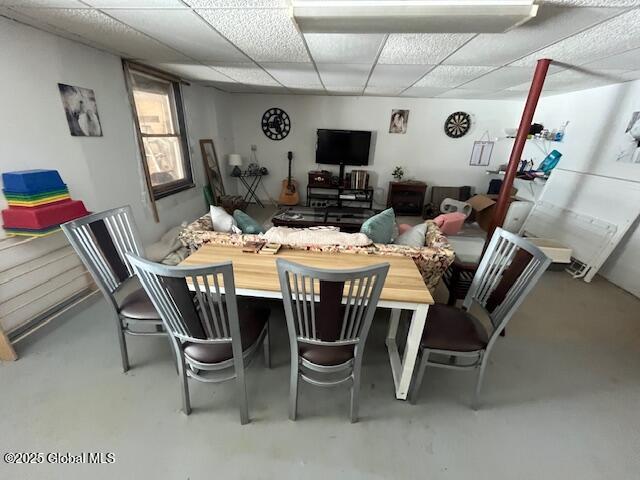 dining space featuring a paneled ceiling and concrete floors