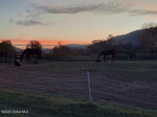 yard at dusk featuring a mountain view and a rural view