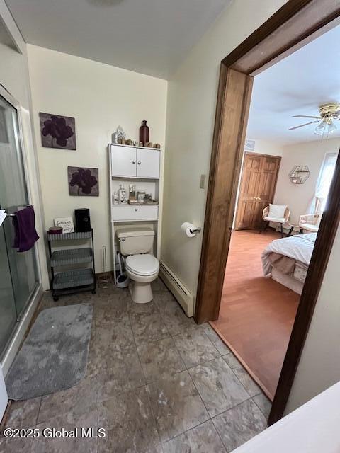 bathroom featuring baseboard heating, ceiling fan, toilet, and an enclosed shower