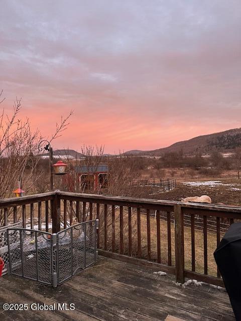 deck at dusk featuring a mountain view and grilling area