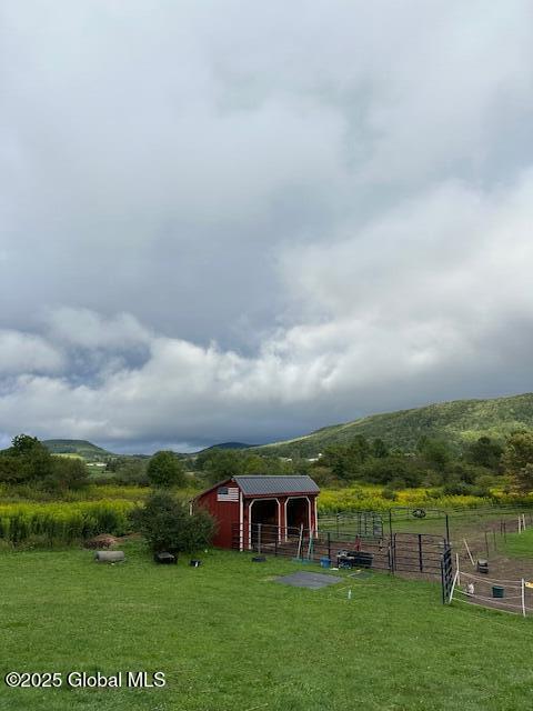 view of yard featuring an outbuilding, a mountain view, and a rural view