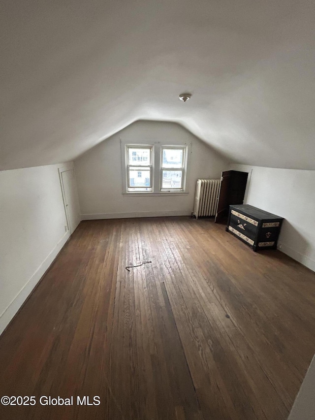 additional living space with radiator, vaulted ceiling, and dark hardwood / wood-style floors