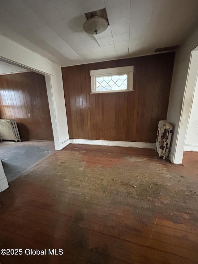 entryway with dark hardwood / wood-style flooring, radiator heating unit, and wooden walls