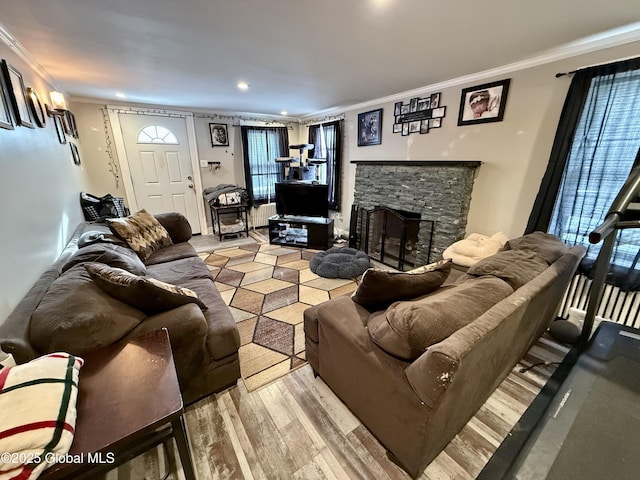 living room with crown molding, a stone fireplace, and light wood-type flooring