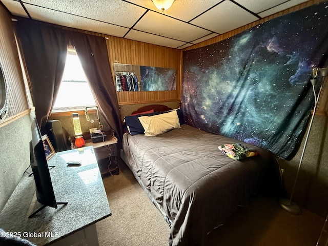 carpeted bedroom with a drop ceiling and wood walls