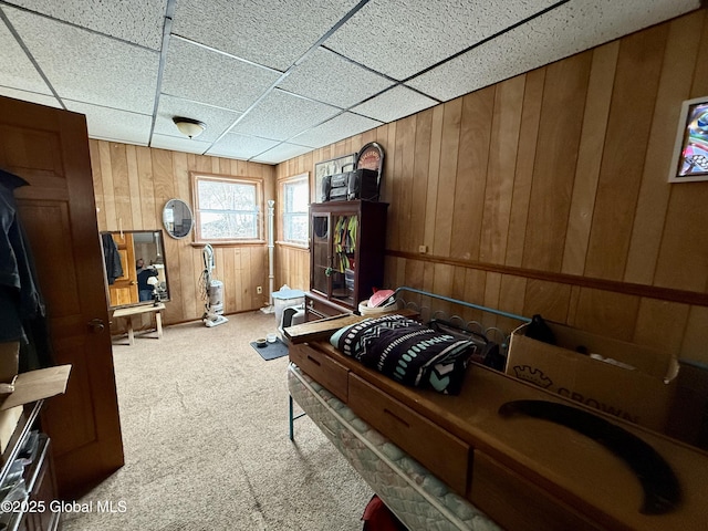 bedroom with a paneled ceiling, wood walls, and carpet