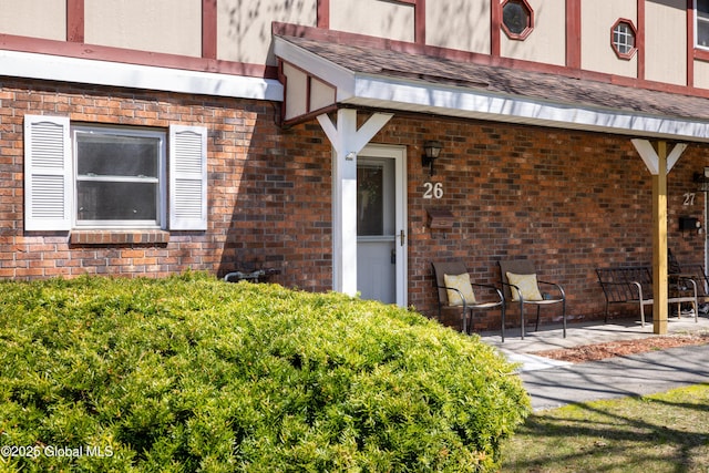 property entrance with brick siding and a patio area