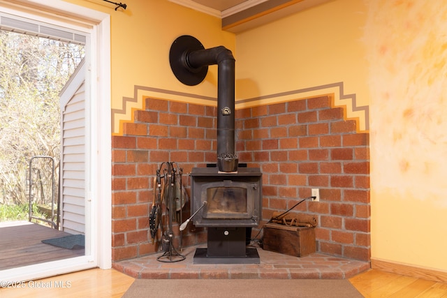 interior details featuring a wood stove, wood finished floors, and ornamental molding