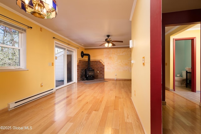 unfurnished living room featuring a baseboard radiator, ceiling fan with notable chandelier, light wood-type flooring, a wood stove, and crown molding
