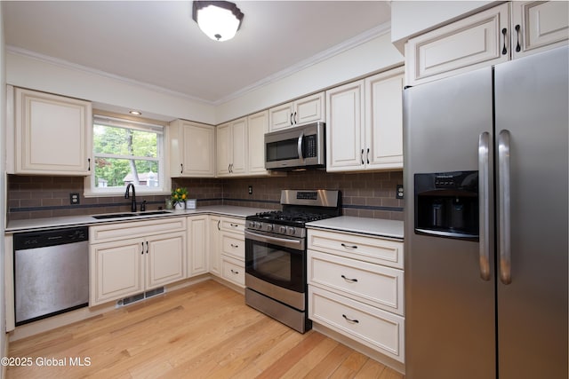 26 Queens Way, Queensbury, NY 12804 - kitchen featuring stainless steel appliances, a sink, ornamental molding, light wood-style floors, and decorative backsplash