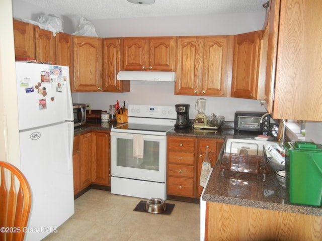 kitchen with white appliances, dark stone counters, and a textured ceiling