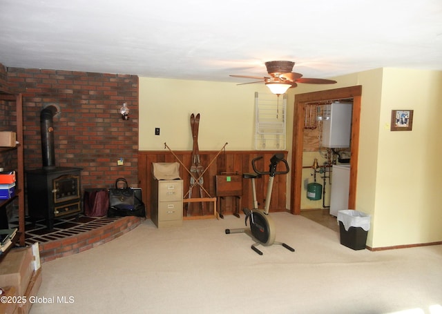 exercise room with ceiling fan, carpet, water heater, and a wood stove