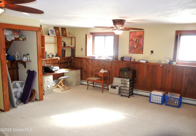 miscellaneous room featuring ceiling fan, a baseboard heating unit, light colored carpet, and wooden walls