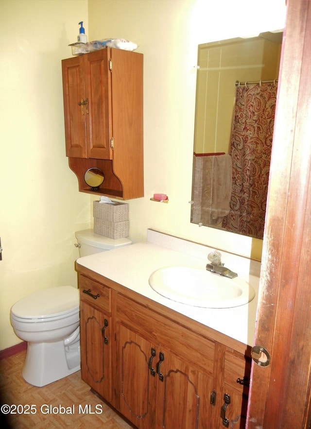 bathroom featuring parquet flooring, vanity, and toilet