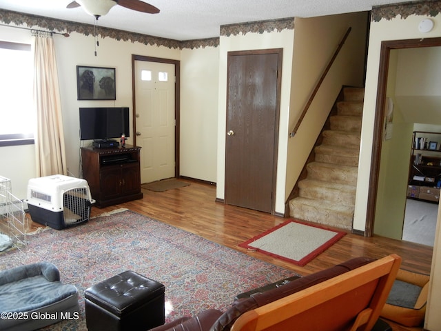 living room featuring ceiling fan, light hardwood / wood-style floors, and a textured ceiling