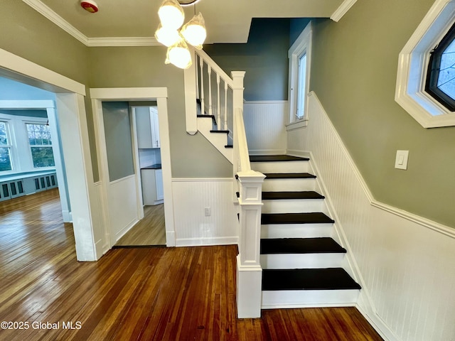 stairs with hardwood / wood-style flooring, ornamental molding, plenty of natural light, and an inviting chandelier