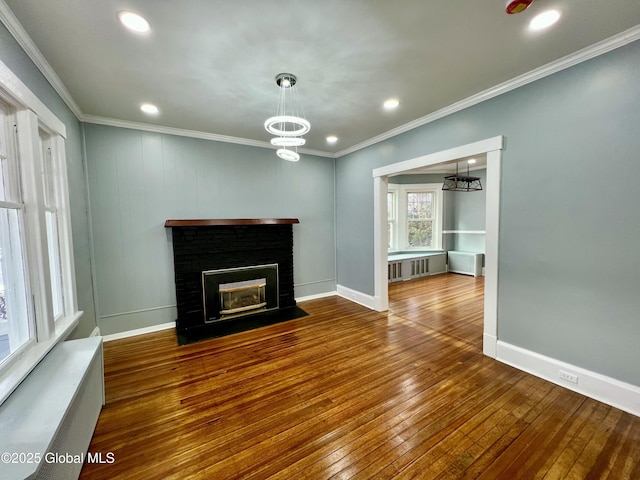 unfurnished living room with an inviting chandelier, crown molding, a fireplace, and wood-type flooring