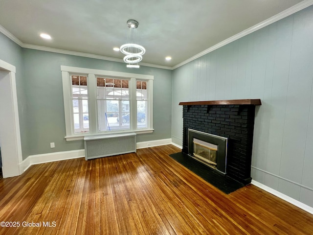 unfurnished living room with crown molding, wood-type flooring, a brick fireplace, radiator heating unit, and a notable chandelier