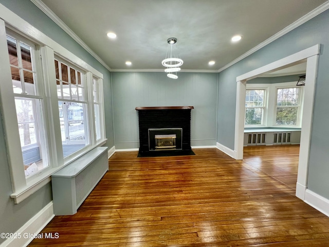 unfurnished living room featuring crown molding, radiator heating unit, dark hardwood / wood-style flooring, and a brick fireplace