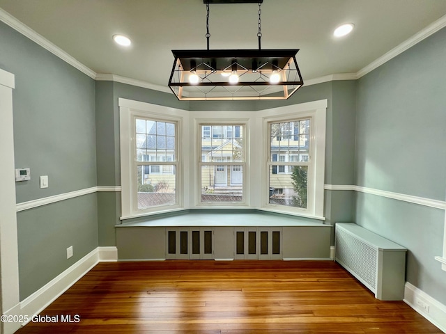 unfurnished dining area with hardwood / wood-style flooring, ornamental molding, and radiator heating unit