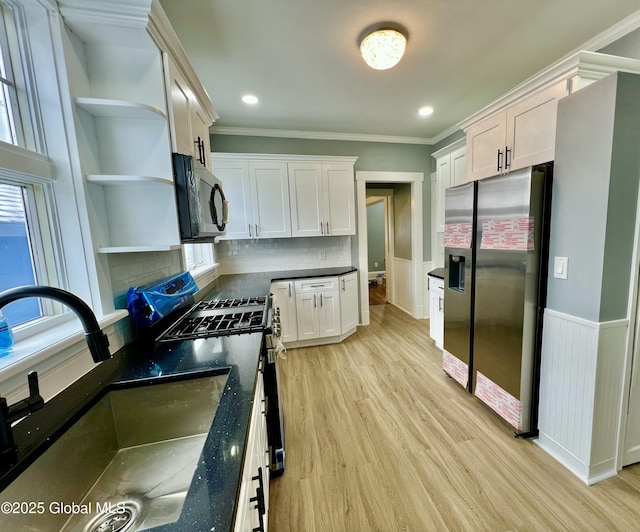 kitchen featuring sink, light hardwood / wood-style flooring, stainless steel refrigerator with ice dispenser, gas range oven, and white cabinets