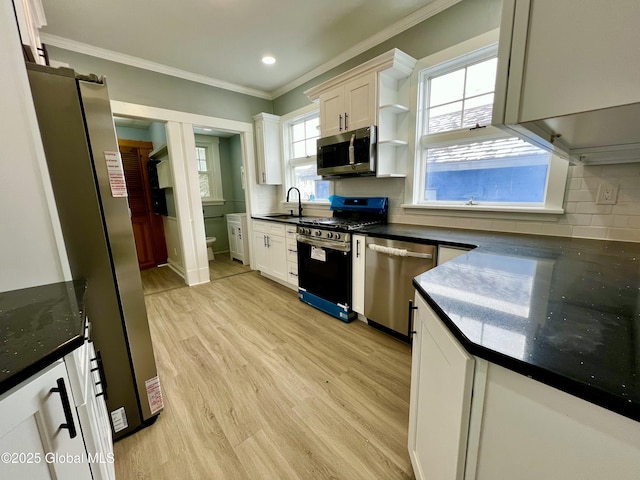 kitchen with white cabinetry, appliances with stainless steel finishes, backsplash, and light wood-type flooring