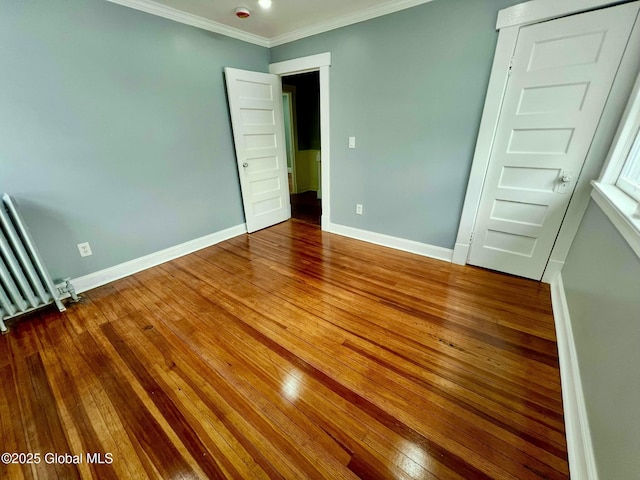 unfurnished bedroom featuring ornamental molding, radiator, and hardwood / wood-style floors