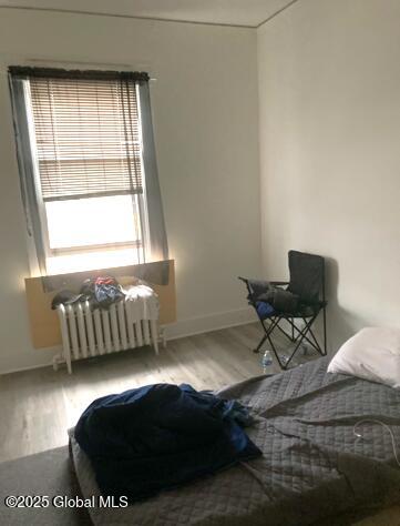 bedroom featuring radiator and hardwood / wood-style flooring