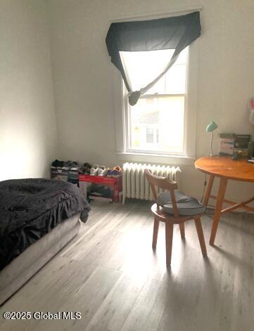 bedroom featuring hardwood / wood-style flooring and radiator heating unit