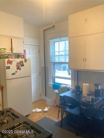 kitchen with white cabinetry, white fridge, and black gas range oven